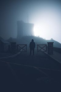 A mysterious silhouette stands in a foggy night landscape, adding drama to a scenic view.