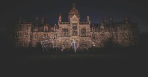 A nighttime photograph of an eerie, abandoned mansion in Wales, exuding a spooky atmosphere.